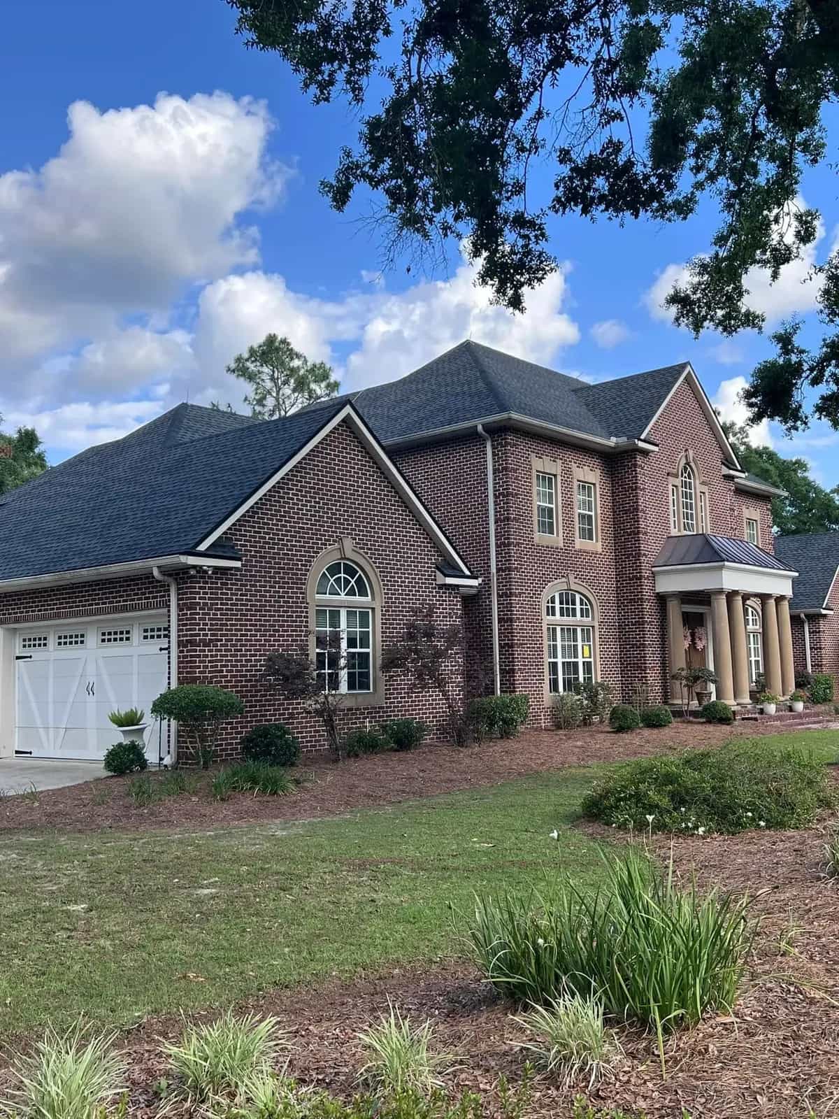 Brick two-story home with a completed dark architectural shingle roof