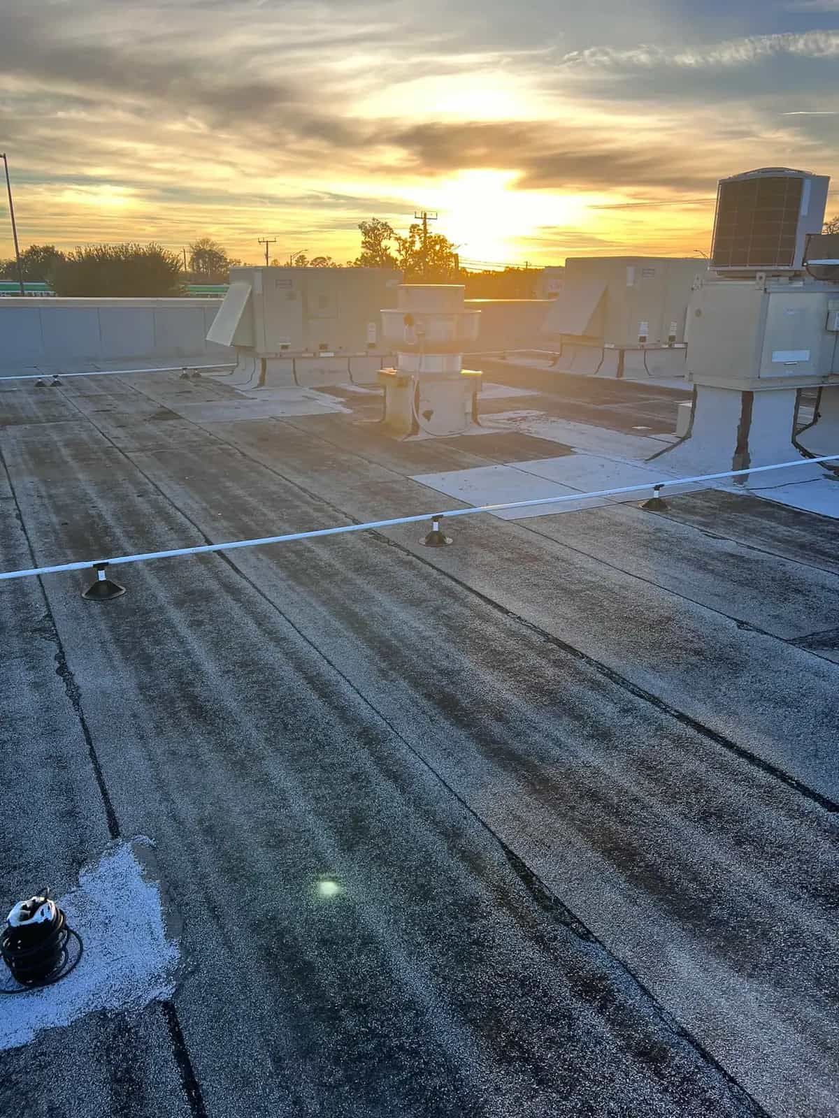 Low-slope commercial roof at sunset with rooftop equipment